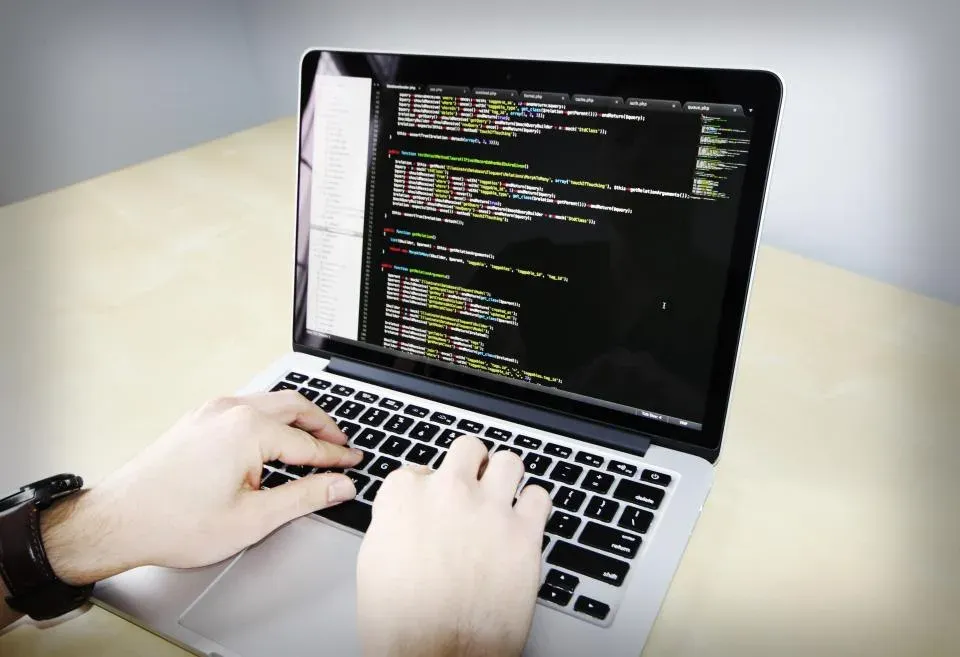 Hands typing code on a laptop