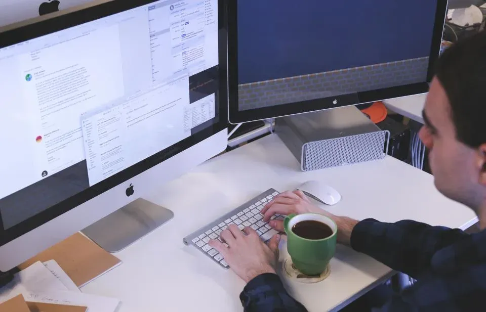Person working across two desktop monitors